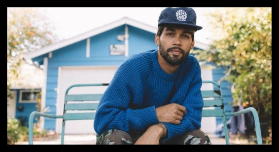 Ryan Ellis kneels in front of a blue home wearing a blue sweatshirt and ball cap